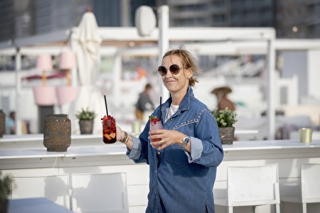 Dame trägt 2 Cocktails im weißen Interieur einer Strandbar