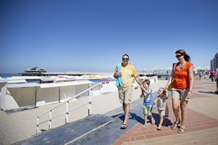 Familie mit Kindern spaziert im Sommer entlang des Deichs.